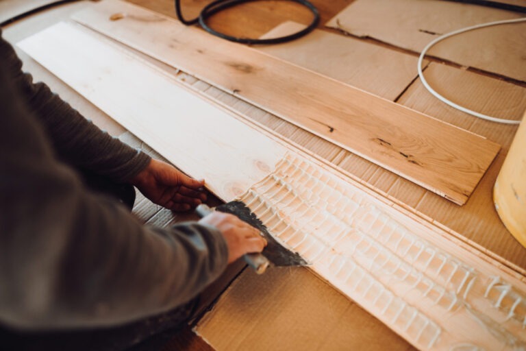 close-up of hand of worker adding glue during parquet installation